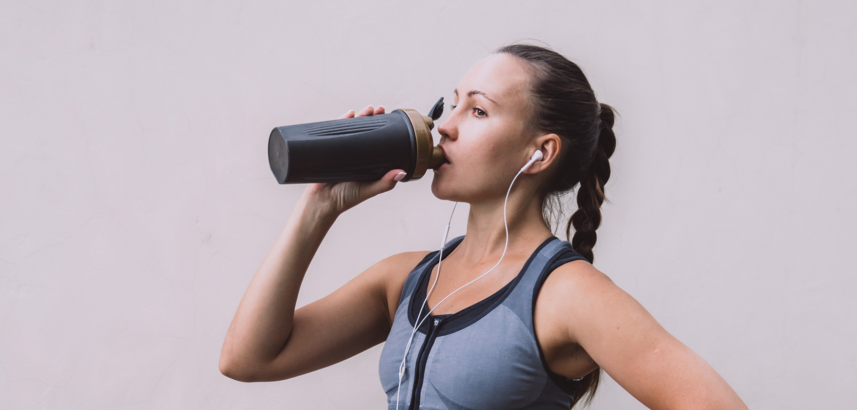 Athletic woman with headphones drinking water. buy weed online in canada. mail order marijuana online dispensary.