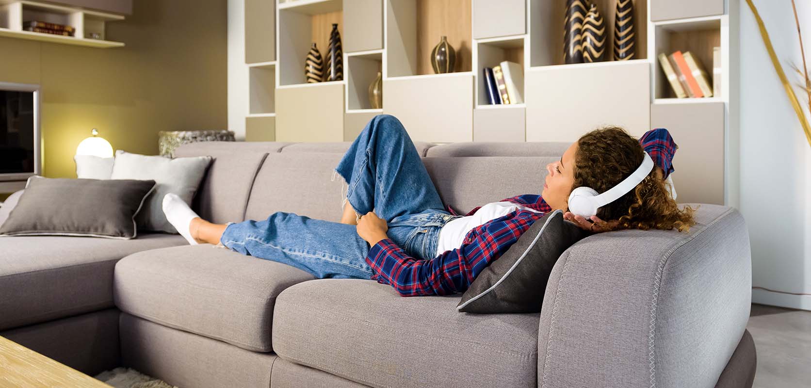 female relaxing on sofa at home with headphones on after buying weed online from Low Price Bud mail order marijuana dispensary Canada.