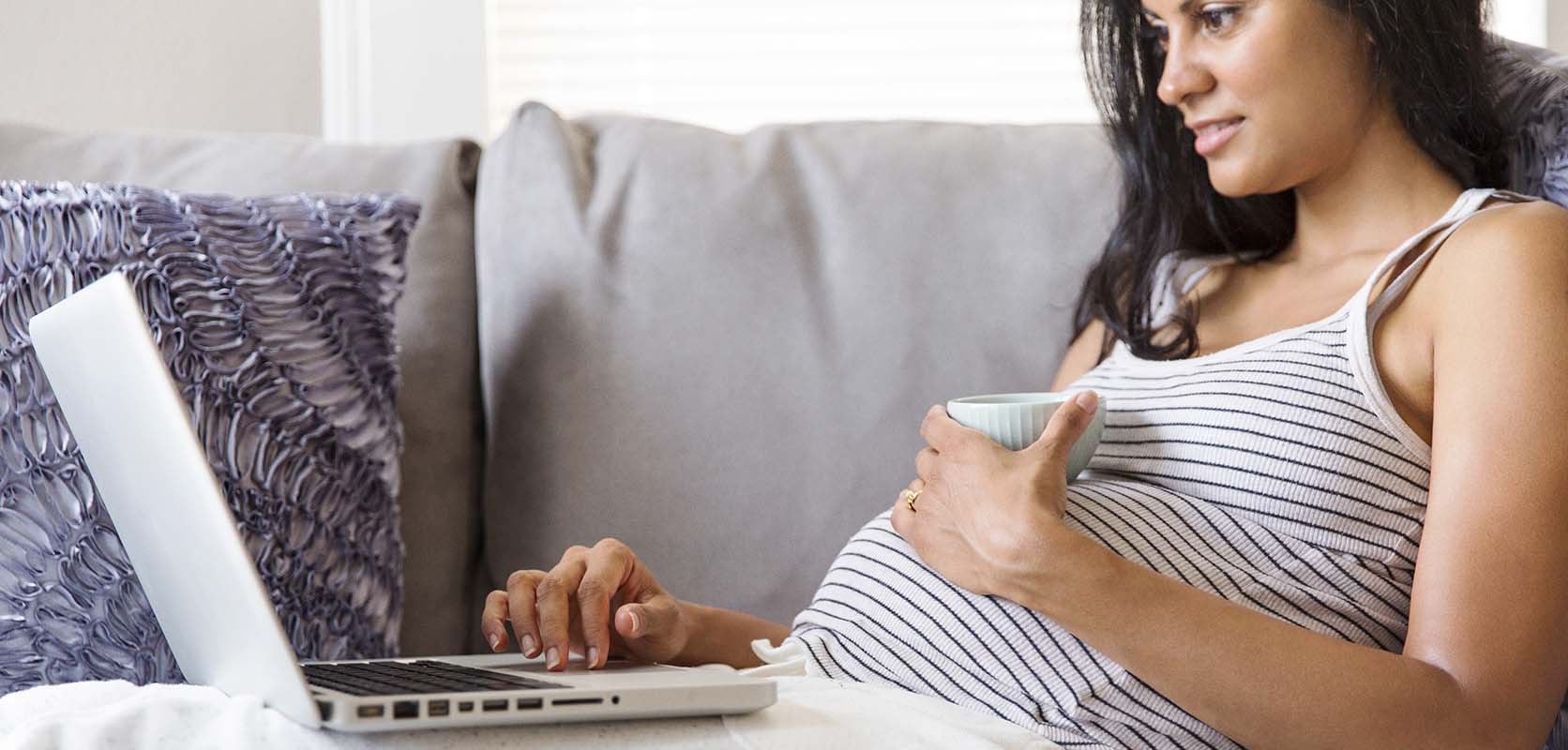 Pregnant woman on laptop searching if smoking marijuana while pregnant will harm the baby.