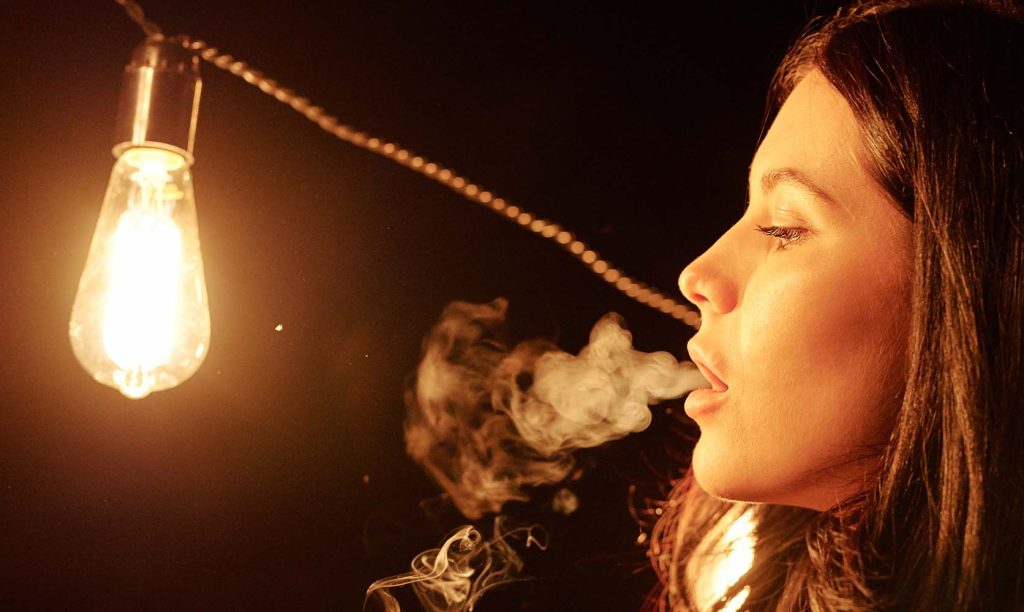 Girl blowing vape clouds after learning how to dab. buy weed online in Canada.