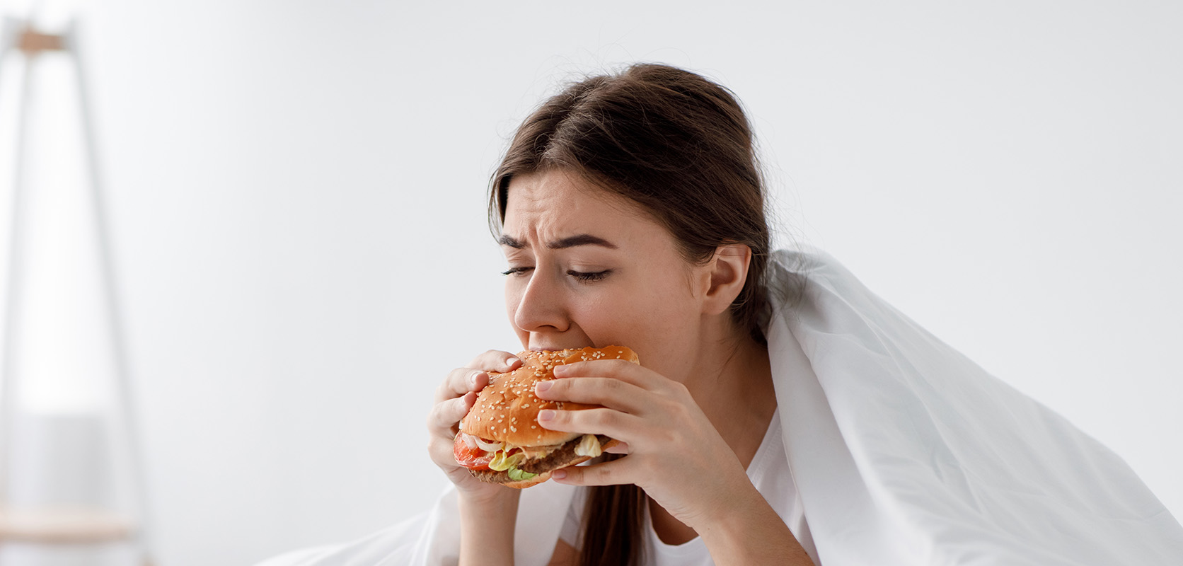 Woman eating a burger at home. buy online weeds. best online dispensary canada. mail order marijuana.