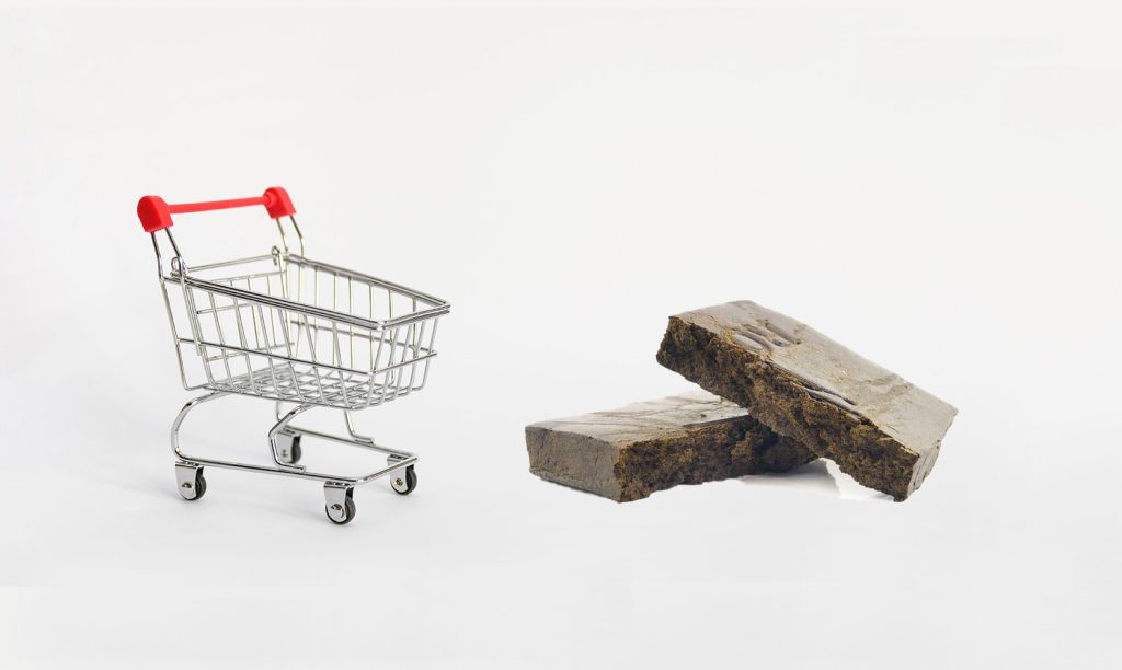 Black hash next to a mini shopping cart. Buy hash online in Canada from low Price Bud online dispensary.