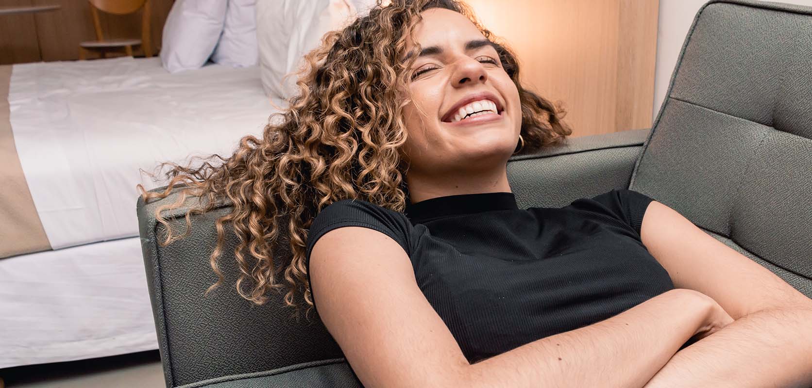 Woman laying on her couch smiling and laughing. weed online canada. order cannabis online. buy weed online.