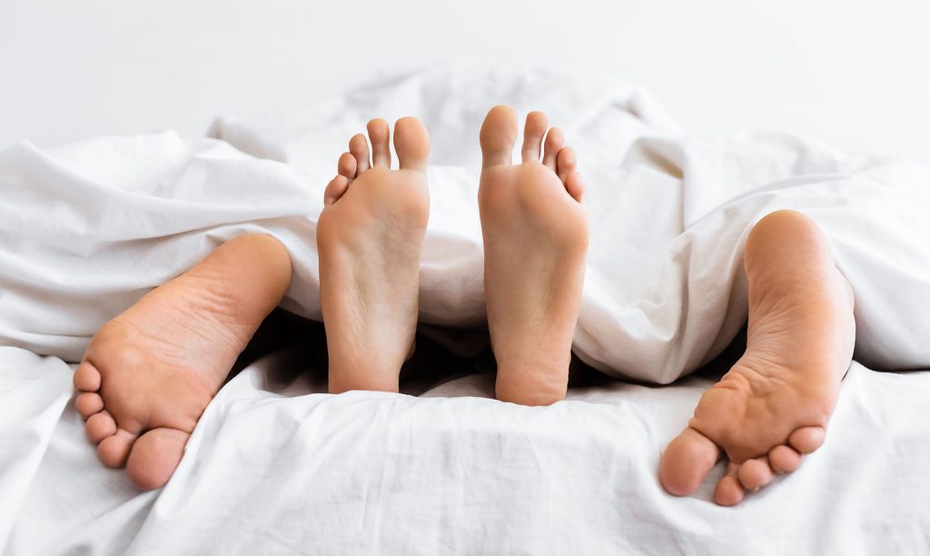 Couples feet in bed. best weed for sex. buy weed online Canada at Low Price Bud dispensary for mail order marijuana.