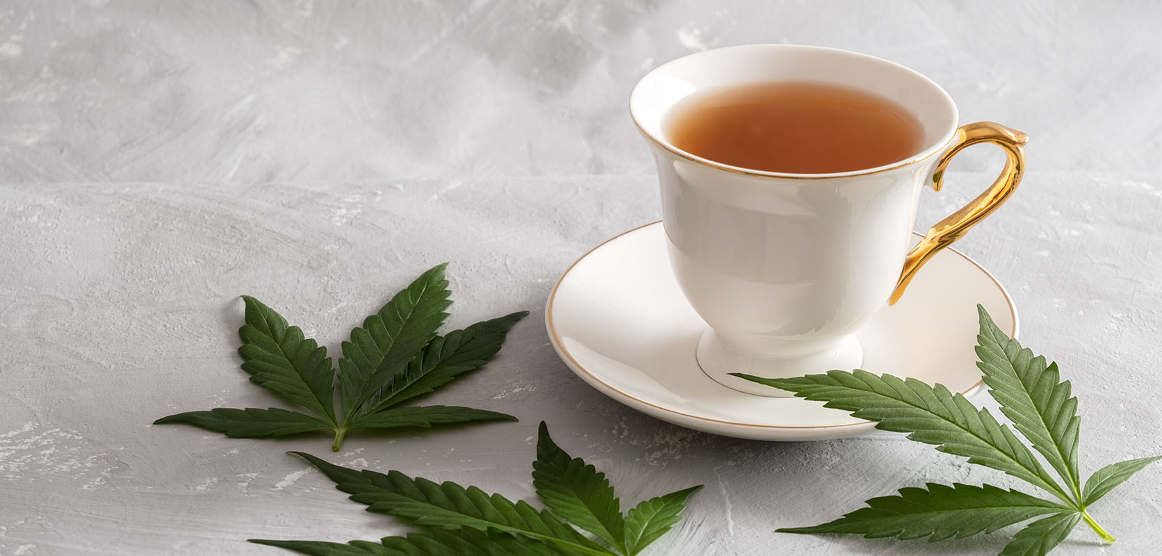 weed tea surrounded by cannabis leaves from an online dispensary in Canada for dispensary weed, THC edibles, gummys, and shatter. Buy weed online.