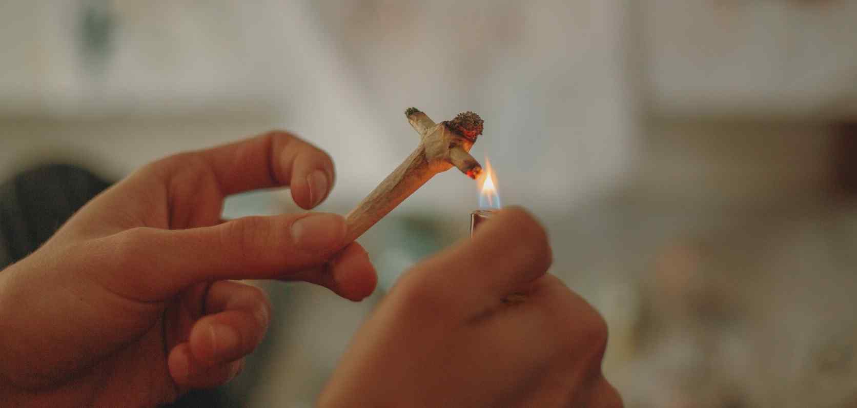 Person lighting a cross joint after they learned how to roll a cross joint from an online dispensary in Canada.